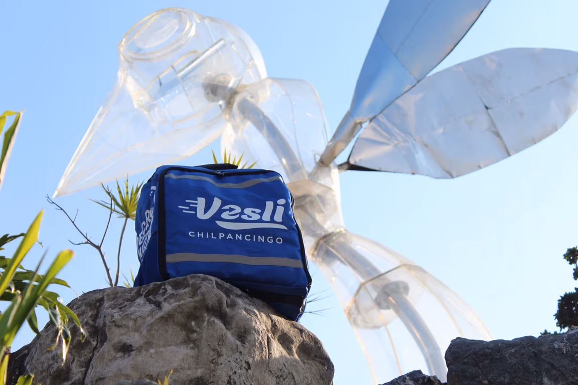 Mochila de reparto de Vesli Chilpancingo sobre una roca, junto a la escultura de la ciudad