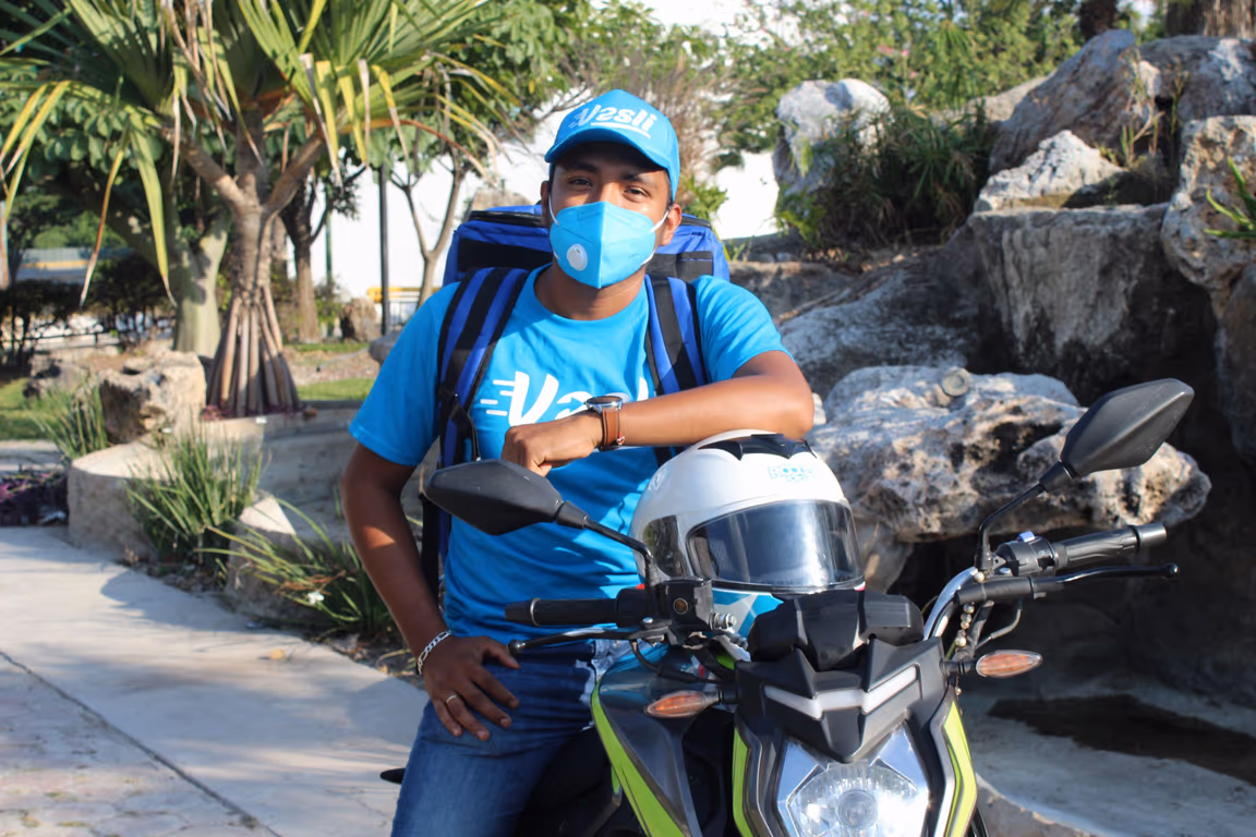 Socio repartidor de Vesli en su motocicleta, con gorra y mochila de reparto