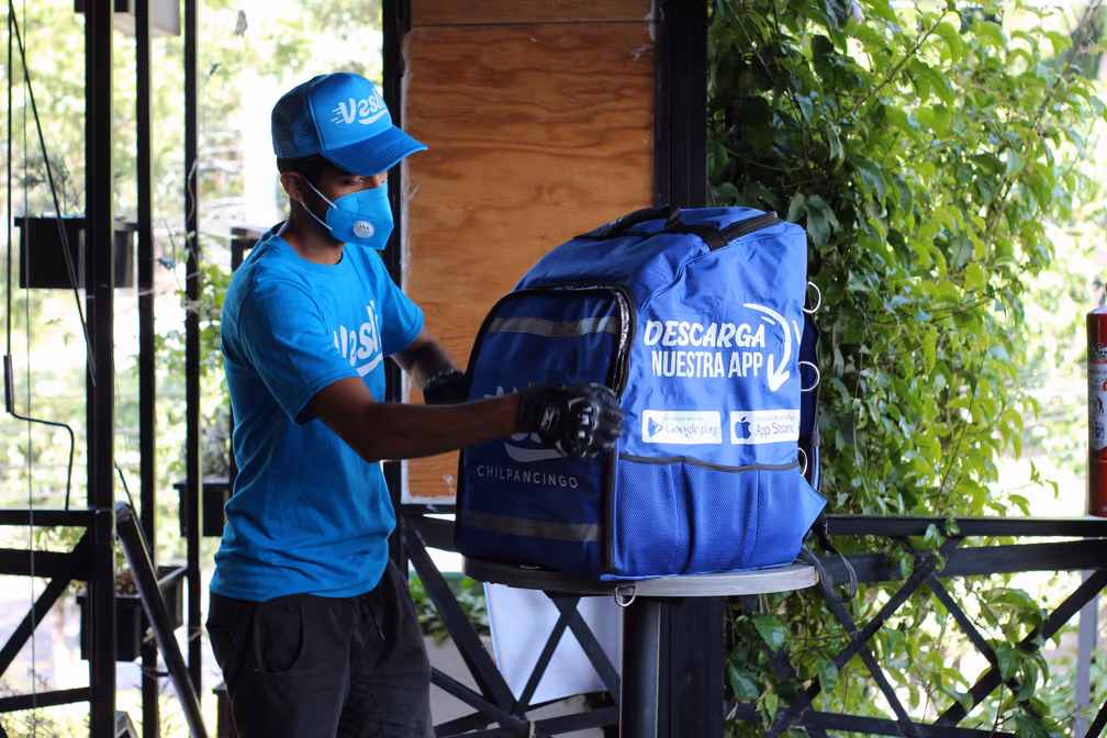 Repartidor de Vesli colocando la mochila con la leyenda Descarga nuestra app
